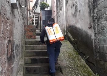 Homem sobe viela para pulverizar produto contra o Coronavírus