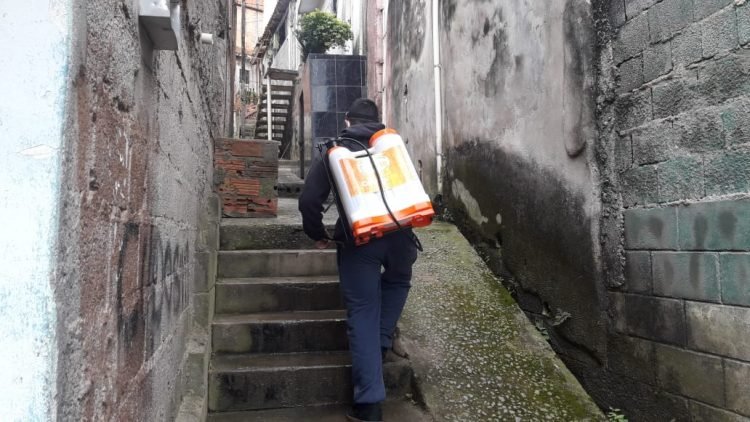 Homem sobe viela para pulverizar produto contra o Coronavírus