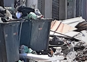 Caçamba está lotada e ao redor há muito entulho depositado