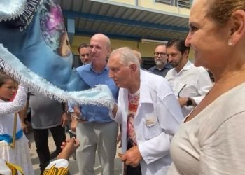 Padre Rosalvino beija o pavilhão da Escola de Samba da Obra Social Dom Bosco