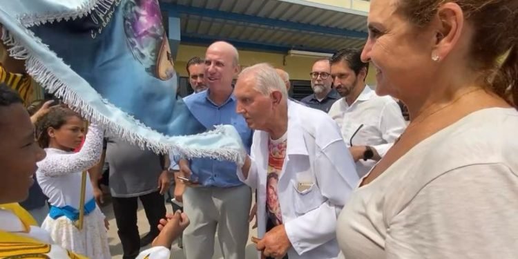 Padre Rosalvino beija o pavilhão da Escola de Samba da Obra Social Dom Bosco