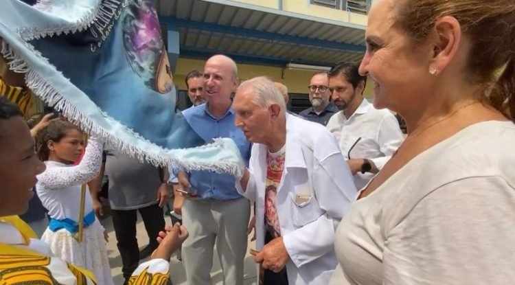 Padre Rosalvino beija o pavilhão da Escola de Samba da Obra Social Dom Bosco